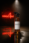 HMU4TINT Pro Slip Solution 16oz — amber spray bottle on wet concrete under red HMU4TINT neon
